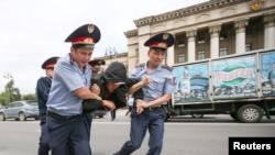 Полицейские несут задержанного на акции протеста в автозак. Алматы, 10 июня 2019 года.