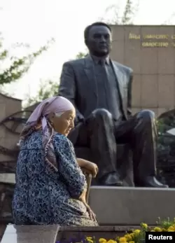Пенсионерка у памятника Назарбаеву в Алматы.